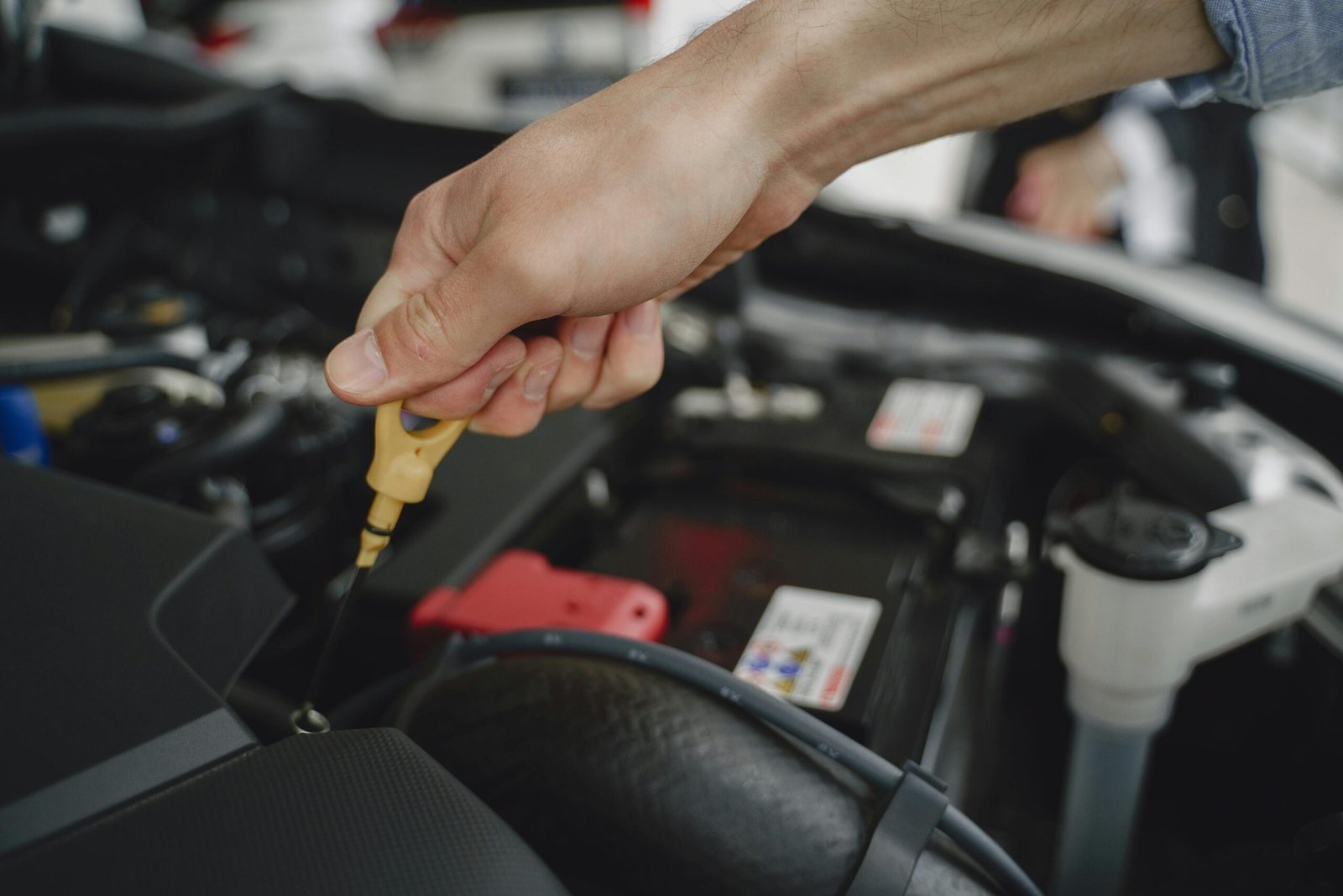 pexels-photo-4895412-4895412 Hand checking oil dipstick in a car engine bay for maintenance and diagnostics.