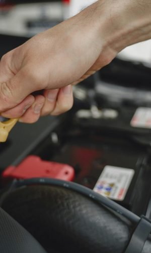 Hand checking oil dipstick in a car engine bay for maintenance and diagnostics.